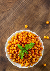 Fried spicy chickpeas in white bowl on wooden table background