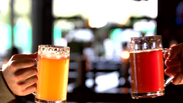 Two men holding beer glasses and clinking. Friends hands clinking pints of beer.