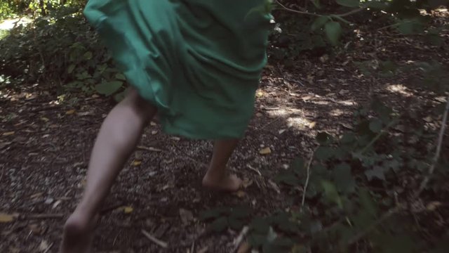 fear, escape, panic. feet of barefoot women running in the woods-slow motion
