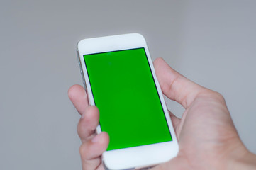 Young man holding a smart phone with green screen