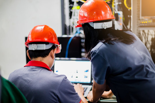 A Portrait Of An Industrial Man And Woman Engineer With Laptop In Control Room Of Factory.