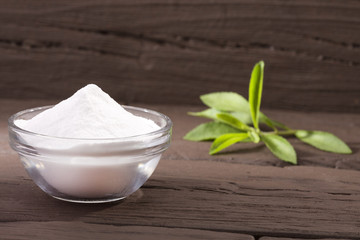 Natural sweetener in powder from stevia plant - Stevia rebaudiana. Wooden background