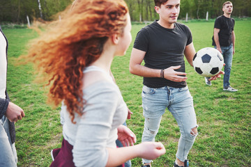 Naklejka premium A group of friends in casual outfit play soccer in the open air. People have fun and have fun. Active rest and scenic sunset