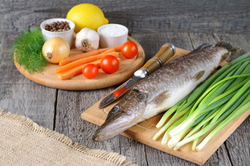 Raw fish on the table among fresh vegetables before cooking.