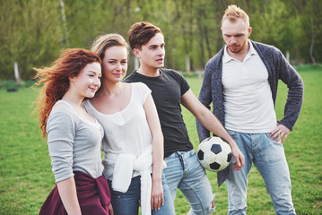A group of friends in casual outfit play soccer in the open air. People have fun and have fun. Active rest and scenic sunset