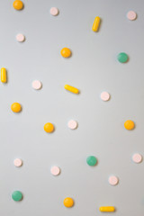 Pattern of white, green and orange pills and tablets on a blue background. Assorted pharmaceutical medicine pills, Flat lay