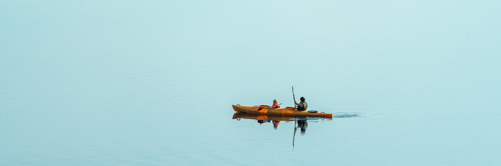 Two people kayaking on a calm lake, panorama © DZiegler