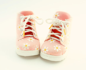Baby pink shoes stand on a white background. Theme of newborns.