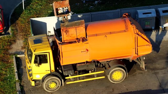 A garbage truck cleans garbage cans in the courtyard of a residential area from garbage and takes it to landfill, dumpster