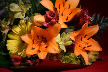 Multi-colored flowers of lilies, asters and green leaves of a fern in the original beautiful bouquet for a gift