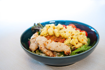 close-up of plate of pasta and chicken with lettuce
