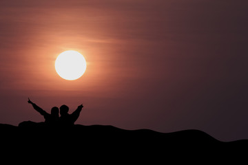 silhouette of man and woman on the mountain with sunset in the evening.