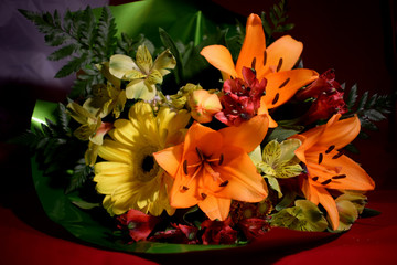 Multi-colored flowers of lilies, asters and green leaves of a fern in the original beautiful bouquet for a gift