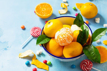 Fresh and juicy tangerines in a bowl and variety of Christmas sweets on blue a concrete background. Copy space.