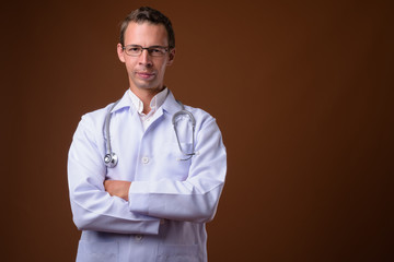 Studio shot of man doctor against brown background