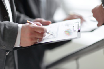 businessman at desk checking a financial report and pointing at