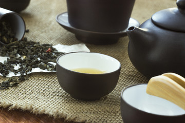 Dipped green flower tea with a cup of white tea on the background of burlap with the accessories of a Chinese tea ceremony