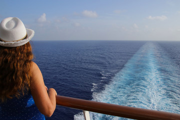 Eine Frau schaut von einem Kreuzfahrtschiff auf das Meer	