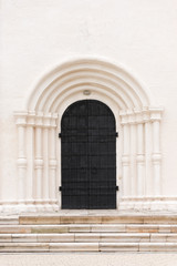 The big black door is the gate to the white building. Architectural details of the past.