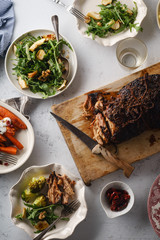 Big festive dinner with slow-roasted pork and various side dishes with vegetables. Overhead view, celebration concept
