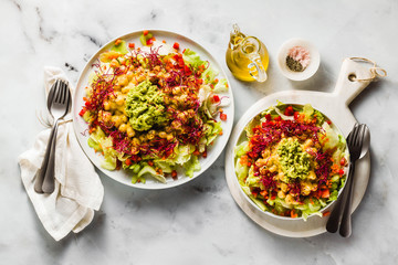Healthy vegan salad with fresh vegetables, sprouts, avocados and chickpeas in mango juice. Raw food for a healthy family
