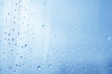 Naklejka na ściany i meble Water rain drop onto the window glass background.
