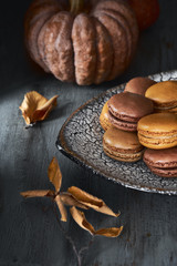 Autumn macarons with caramel and cocoa with coffee on dark rustic wood