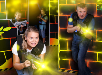 Excited young girl aiming laser gun at other players during lase
