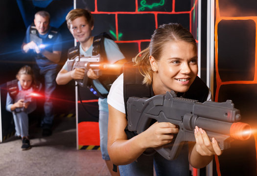 Happy young girl with laser gun  during laser tag game with  pla