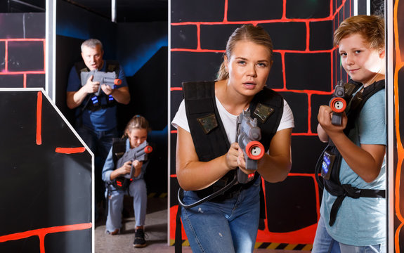 Happy teen boy having fun on laser tag arena with his older sister