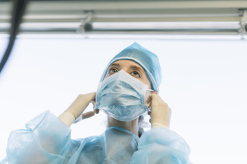 Fototapeta na wymiar Young beautiful woman, nurse, doctor, in mask, white blue background.. contagious virus disease concept