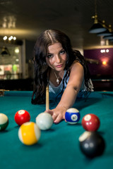 Pretty and young woman playing billiard in pub