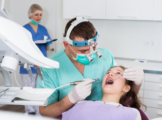 Confident male dentist treating girl