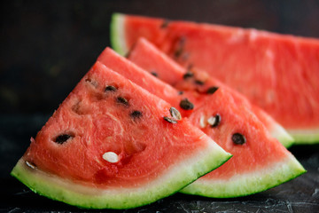 Slices of fresh ripe watermelon on a dark background.