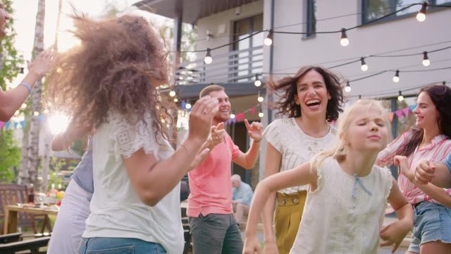 Family and Friends Dancing together at the Garden Party Celebration. Adults and Children Having Fun on a Sunny Summer Day Disco.