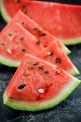 Slices of fresh ripe watermelon on a dark background.