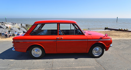Classic Red Hillman Imp Motor Car parked on seafront promenade.