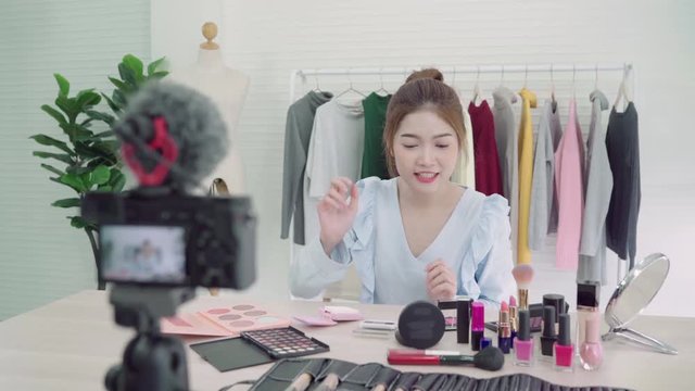 Beauty blogger present beauty cosmetics sitting in front camera for recording video. Beautiful asian woman use cosmetics while review make up tutorial broadcast live video to social network