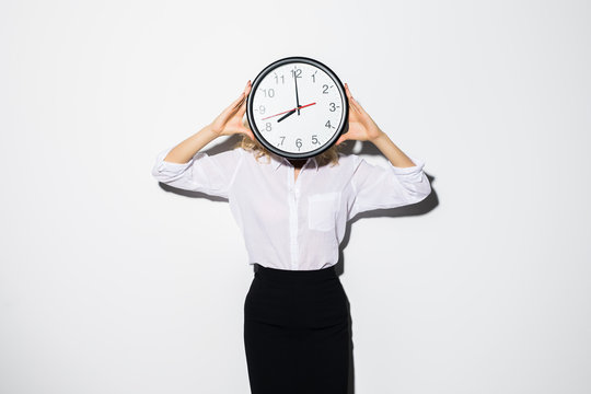 Young business woman covering face with clock standing isolated over white background .