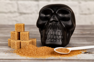 Harm of sugar concept.  Cubes of sugar and black skull figure