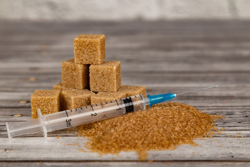 Addiction to sugar concept. Cubes of brown sugar and syringe