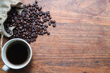 Top view of Coffee in white cup and coffee beans on wooden table with copy space for text or image