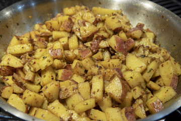 Potato being cooked in a hot pan closeup