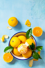 Fresh and juicy tangerines in a bowl on blue a stone or slate background. Seasonal, food background. Top view flat lay background. Copy space. © elena_hramowa