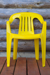 Obraz na płótnie Canvas Yellow plastic chair on the background of wooden wall