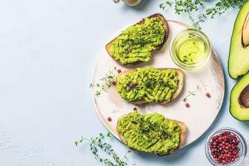Healthy breakfast, avocado toasts on cutting board. Top view, space for text.