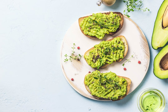 Healthy breakfast, avocado toasts on cutting board. Top view, space for text.