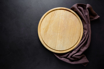 Round сatting board with ingredients for cooking and knife on dark wooden background. Top view. Copy space.