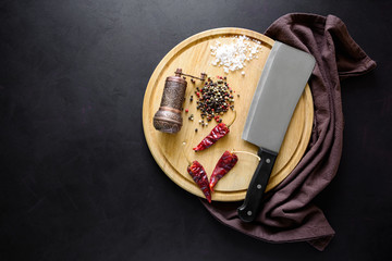 Round сatting board with ingredients for cooking and knife on dark wooden background. Top view. Copy space.