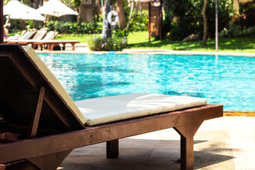 Sunbed with beach umbrella on side of swimming pool. Relaxing facility.